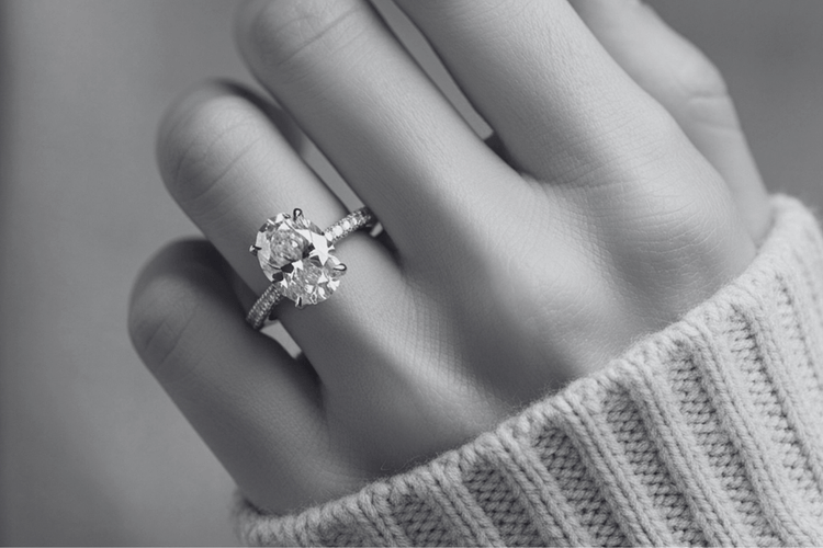 Close-up of a hand wearing a diamond ring with a blurred background