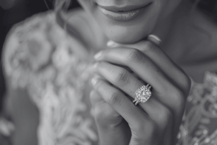 Close-up of a hand wearing a diamond ring with a blurred background