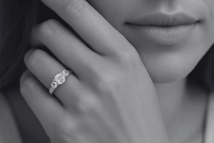 Close-up of a hand wearing a diamond ring with a blurred background