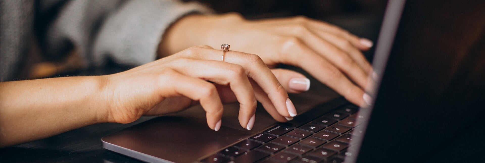 Close-up of hands typing on a laptop with a blurred background