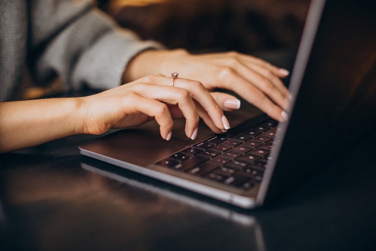Close-up of hands typing on a laptop keyboard with a blurred background