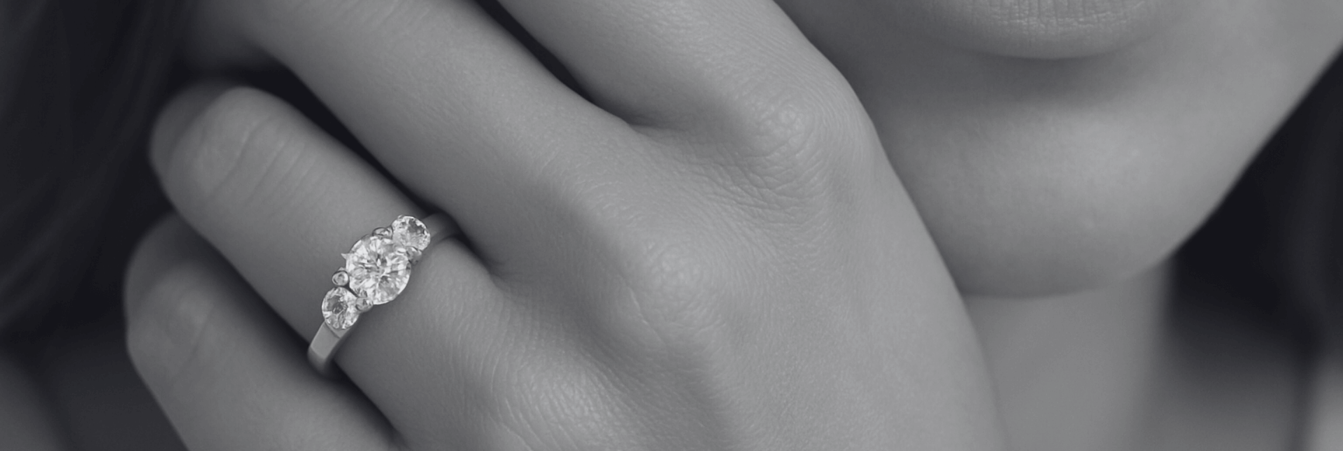 Close-up of a hand wearing a diamond ring with a blurred background